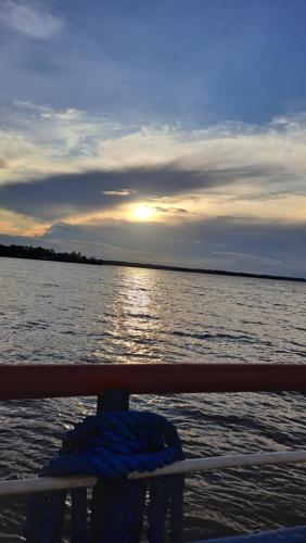 a boat with the sun setting on the water at Casa de Praia Guajarino - COP 30 in Barcarena