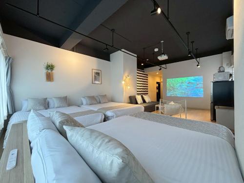 Neighbor's Hotel 西広島駅前 في هيروشيما: غرفة معيشة بها سريرين وأريكة