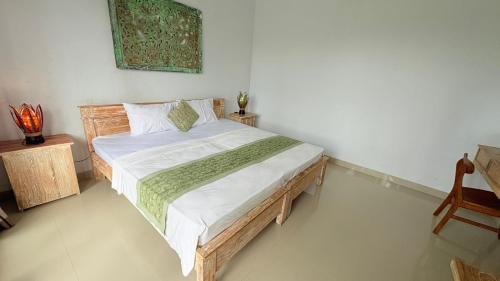 a bedroom with a wooden bed with white sheets at Uma Luwih Villa in Ubud