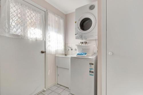 a white kitchen with a washing machine and a microwave at Wood Street Central - Central location! in Bright
