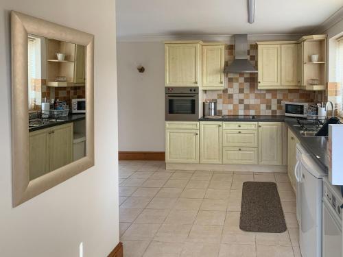 a kitchen with wooden cabinets and a tile floor at Nursery Cottage in North Somercotes