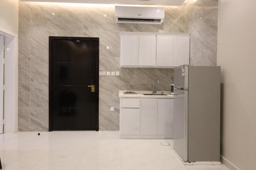 a kitchen with white cabinets and a black door at سويت للشقق الخاصة in Al Madinah