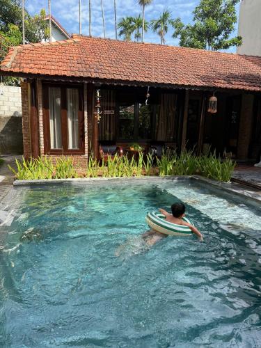 un hombre con una tabla de surf en una piscina en DeMin Villa Hội An - Pool and BBQ Garden, en Hoi An
