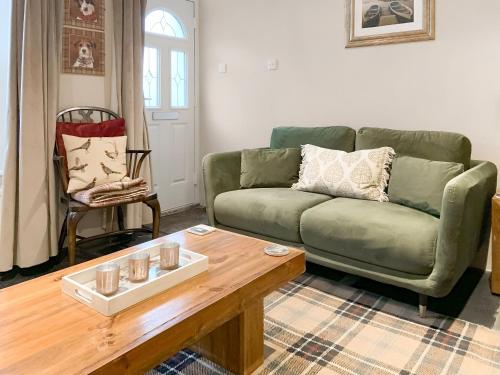 a living room with a green couch and a coffee table at Betsy Cottage in Windermere