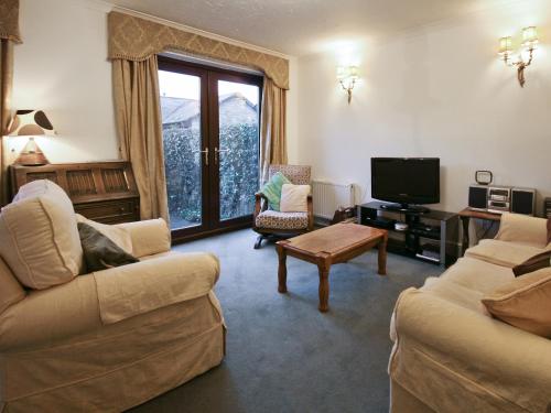 a living room with two couches and a television at Maltings Cottage in Rothbury