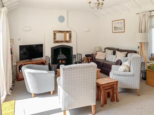 a living room with a couch and chairs and a tv at September Cottage in Brancaster