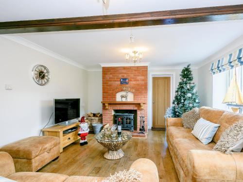 a living room with a fireplace and a christmas tree at Corner House in Cromer