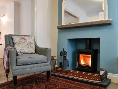 Una sala de estar con una silla y una chimenea. en Applegarth, en Cockermouth