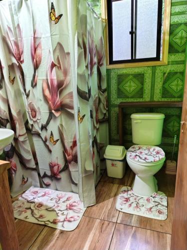 a bathroom with a toilet and a flower shower curtain at Cabaña acogedora en liquiñe in Liquiñe