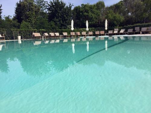 a large swimming pool with chairs and blue water at Il Podere Del Germano Reale in Coriano