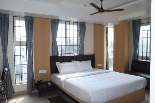 a bedroom with a large white bed with windows at Fern Inn Hotel in Kolkata