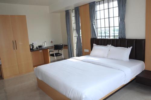 a bedroom with a large white bed with a window at Fern Inn Hotel in Kolkata