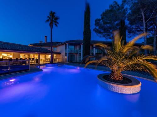 a swimming pool with a palm tree in front of a house at Garrigae Domaine de l'Esterel - piscine & SPA Cinq Mondes in Saint-Raphaël