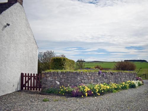 a stone retaining wall with flowers next to a building at South House in Radernie