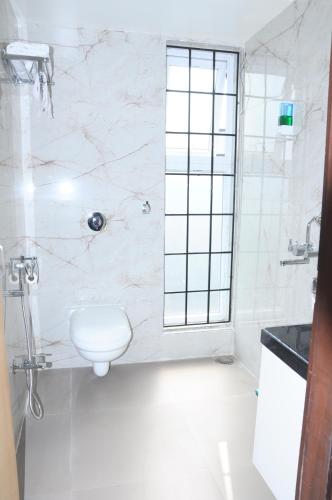 a white bathroom with a toilet and a shower at Fern Inn Hotel in Kolkata