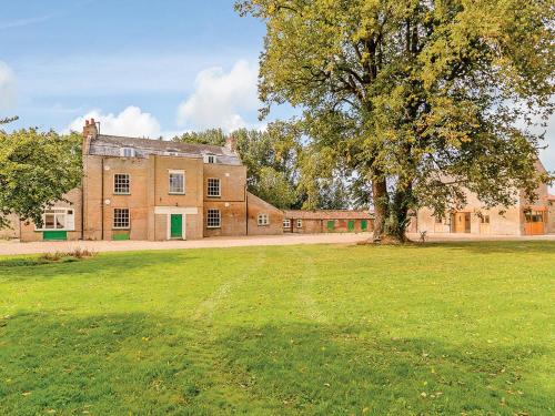 a large brick building with a tree in a field at Lode Hall in Upwell