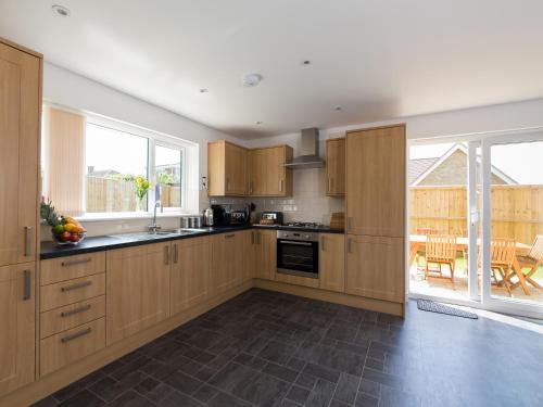 una cocina con armarios de madera y una gran ventana en Downs View, en Sandown