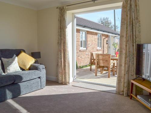 a living room with a couch and a sliding glass door at The Old Bull Pen in Appleshaw