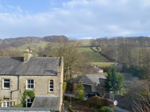 a house in a village with a road and trees at Low Fold Cottage in Stainforth