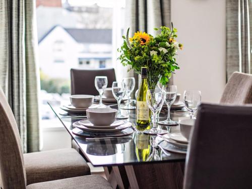 a table with glasses and a vase of flowers on it at Dyma Y Bywyd in Tenby
