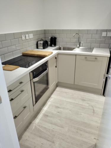 a kitchen with white cabinets and a sink at Glasgow Hampden Garden Flat in Glasgow