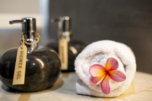 a towel with a flower on it next to a bottle at Nusa Djiwa in Tanah Lot