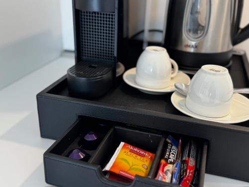 una caja negra con dos tazas, platos y libros en SkyHigh Park View Residence, en Nicosia