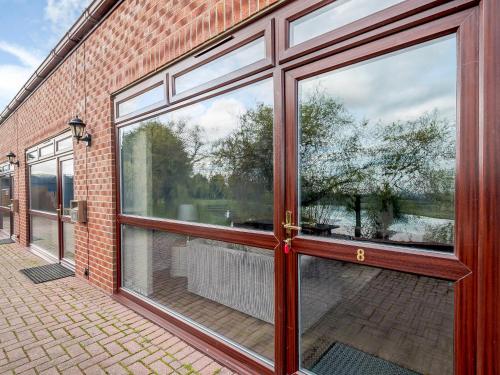 a large glass door in a brick building with a reflection of a tree at Cottage 8 - Uk38219 in Ashby cum Fenby