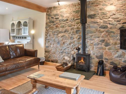 a living room with a stone wall with a wood stove at 1, The Barns in Threlkeld