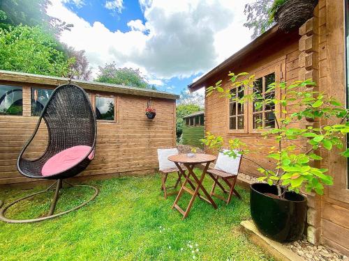 a patio with a chair and a table in the grass at The Cabin in Trowbridge