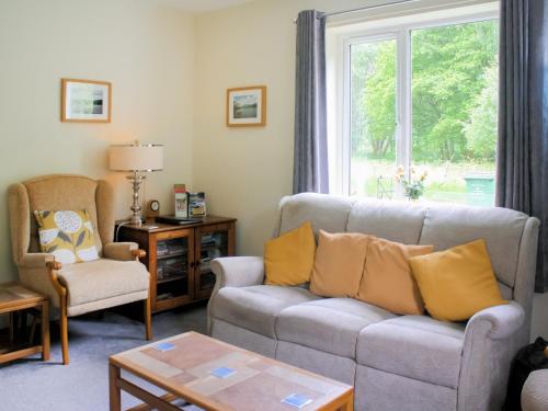 ein Wohnzimmer mit einem Sofa, Stühlen und einem Fenster in der Unterkunft Riversdale Cottage in Saint Fillans