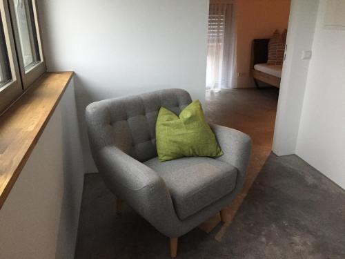 a gray chair with a green pillow in a room at Ferien- Und Winzerhof Simon in Freiburg im Breisgau