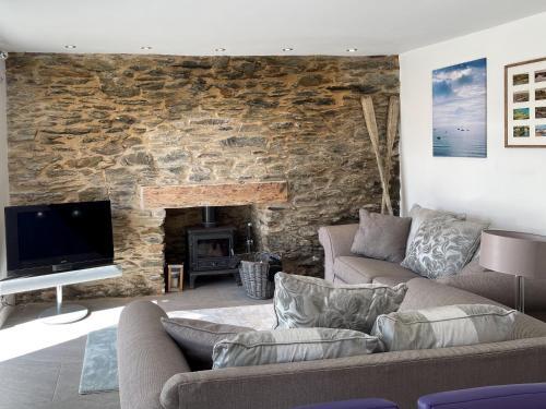 a living room with a couch and a stone wall at Seatons Rest in Portmellon
