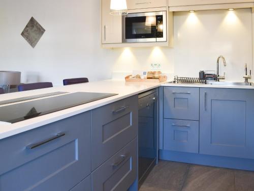 a kitchen with blue cabinets and a sink at Seatons Rest in Portmellon