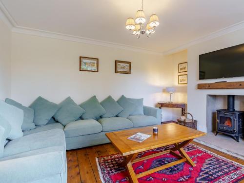 a living room with a blue couch and a table at Brookleigh Farm Cottage in Burley in Wharfedale