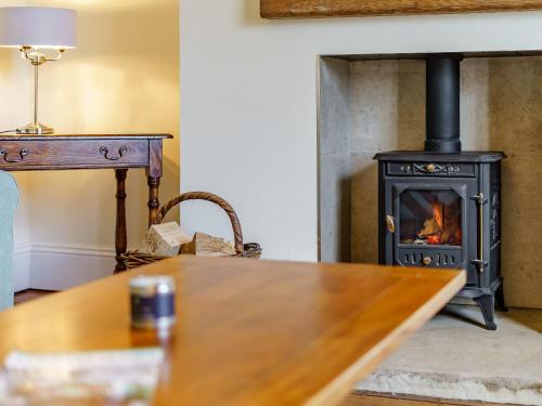 a wood stove in a living room with a table at Brookleigh Farm Cottage in Burley in Wharfedale