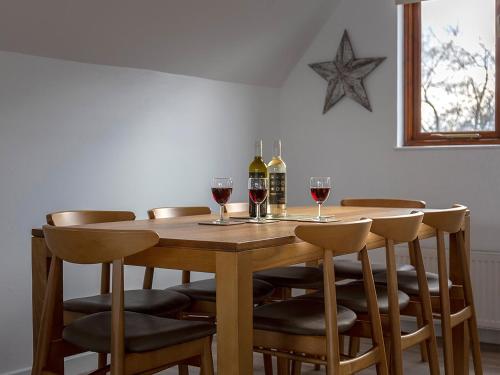 a wooden table with two bottles and glasses of wine at Coot in Wroxham