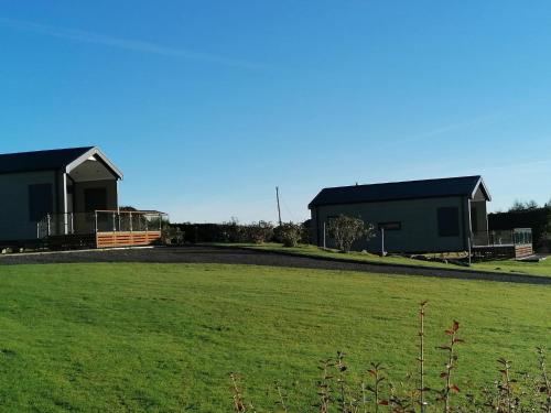two buildings in a field with a green field at Lake Vyrnwy Luxury Pod in Llanwddyn