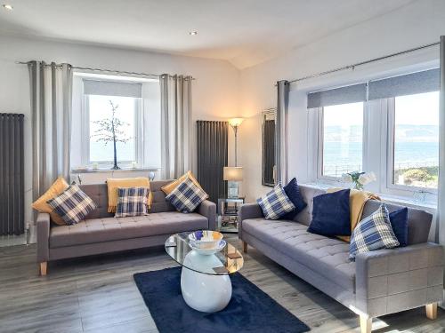 a living room with two couches and two windows at Strathclyde Cottage North in Skelmorlie