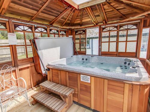 a jacuzzi tub in a wooden room with a bench at Four Oaks in Bransgore