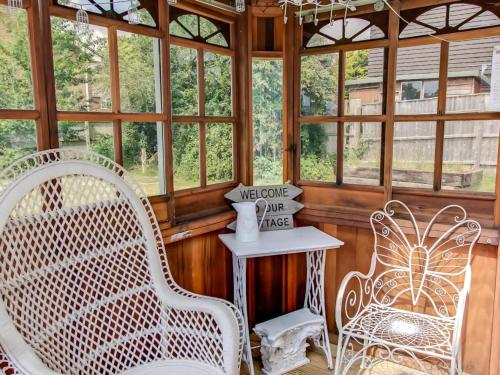 a room with two chairs and a table and windows at Four Oaks in Bransgore