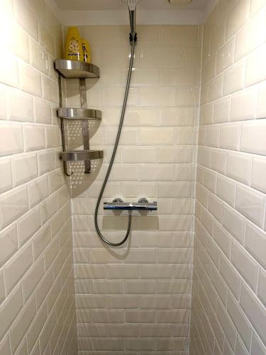 a shower with a hose in a white tiled bathroom at Cosy Studio, with outdoor swimming in Amsterdam