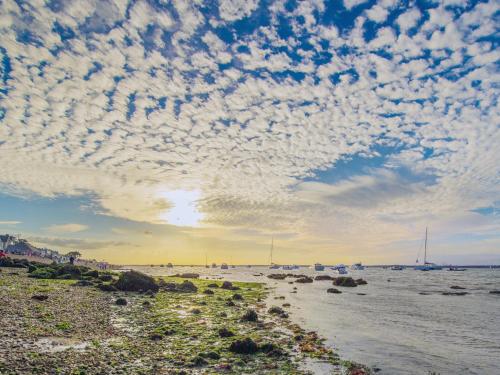 una playa con un cielo nublado sobre el agua en Squirrelstone, en Gurnard