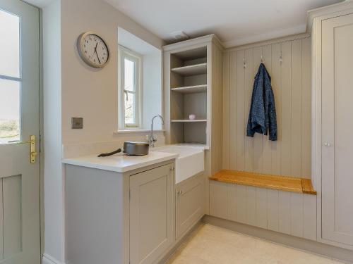 a kitchen with a sink and a clock on the wall at Bwlchsais in Hermon