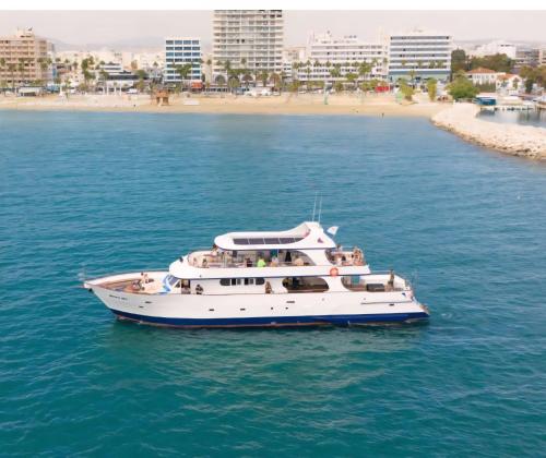 a white boat in the water near a beach at Larnaca Mansion Ideal for 3 Families or more in Larnaka