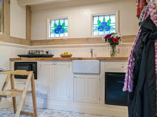 a kitchen with white cabinets and stained glass windows at Jacobs Folly-Qu7115 in Melton Constable