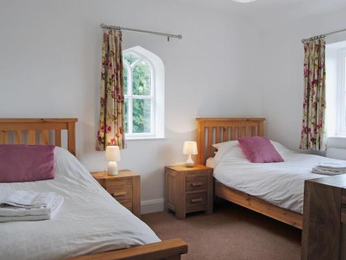 two beds in a bedroom with two lamps and a window at 1 Piccadilly in Trefonen