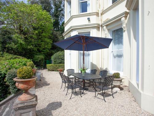 a table with chairs and an umbrella on a patio at Longcroft House in Torquay