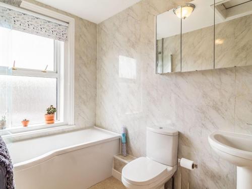 a bathroom with a toilet and a sink and a tub at Riversdelle in Beccles