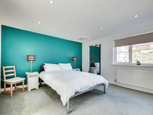 a bedroom with a large bed and a blue wall at The Old Forge - Muz in Wooler